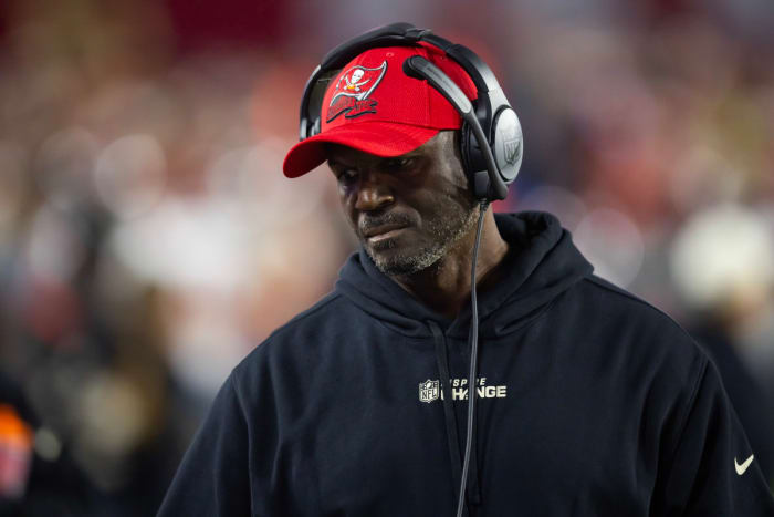 Tampa Bay Buccaneers head coach Todd Bowles looks down wearing a headset and a hat